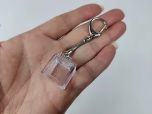 Detailed view of a transparent mechanical keyboard switch tester keychain base in hand.