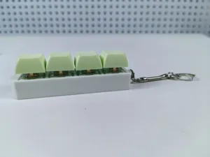 Detailed side view of a 4-key mechanical keyboard switch keychain with green keycaps
