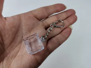Close-up of a clear transparent mechanical keyboard switch tester frame keychain in hand