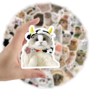 Close-up detail of a cute realistic cat sticker with a cow hat held by a hand for scale
