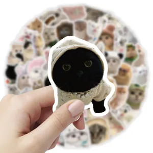 Hand holding a cute black kitten sticker wearing a beige hoodie and pearl necklace