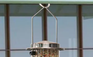 Close-up view of a metal hanging bird feeder detail with clear seed container for outdoor use.