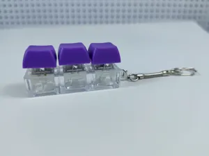 Μπρελόκ fidget διακόπτη μηχανικού πληκτρολογίου με μωβ πλήκτρα και διαφανή βάση.