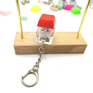 Stress relief mechanical switch keychain featuring a red keycap on a premium wooden stand