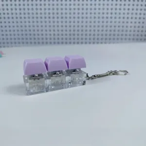 Μπρελόκ fidget μηχανικού πληκτρολογίου με τρία μοβ πλήκτρα και διαφανή βάση αντιστρές.