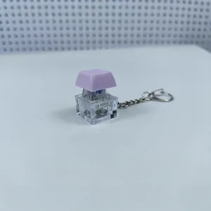 Mechanical keyboard switch fidget keychain with purple keycap, transparent housing, and LED light.