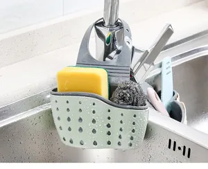 Detailopname van de groene siliconen gootsteenorganizer hangend aan kraan met spons.