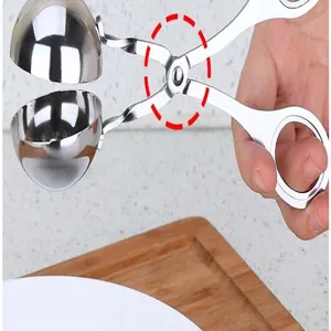 Stainless steel meatball maker hinge detail and dual spoon clamp tool for easy kitchen cooking.