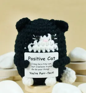 Close-up detail shot of the handmade crochet black and white cat holding a positive card.