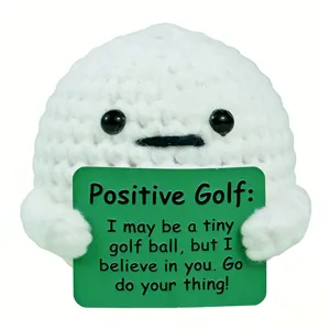 Primo piano di una bambola da golf all'uncinetto con un biglietto motivazionale 'Positive Golf'.
