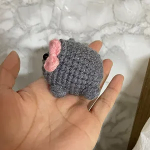 Detailed close-up of a cute handmade crochet sad hamster plush toy with gray yarn.