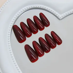 Detailopname van wijnrode kattenoog kunstnagels met glanzende robijnrode finish op spiegel.