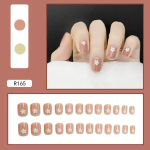 High-resolution detail view of nude pink press-on nails with white daisy flower patterns