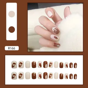 Detail view of stylish brown press-on nails featuring cute floral and chocolate drip designs
