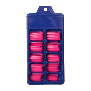 Vista detallada de uñas postizas largas tipo bailarina rosas en una caja de plástico azul
