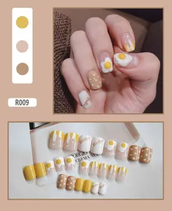 Cute wearable press-on nails featuring poached egg and polka dot patterns in warm yellow tones