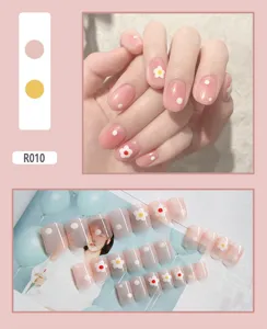 Detail view of 24-piece pink press-on nail set featuring white flower and dot designs