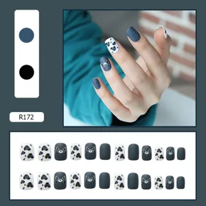 Detailed close-up of matte navy blue and cow print press-on nails set for manicure
