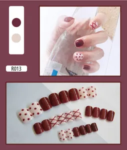 Detailed view of burgundy and cream false nails with polka dots and cross patterns.