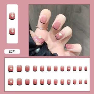 Detailansicht von rosa Ombre-Kunstnägeln mit Herz-Dekor und schwarzen French-Spitzen