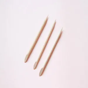 Close-up detail of three disposable orange wood cuticle sticks for nail art cleaning