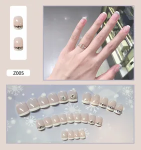 Détail de faux ongles French manucure nude décorés de strass et motifs de fleurs