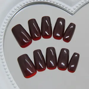 Detailweergave van glanzende donker bordeauxrode kunstnagels op een hartvormige spiegel.