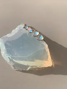 Macro detail of iridescent moonstone heart stud earrings displayed on a crystal stone base