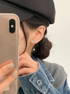 Close-up of a delicate heart-shaped moonstone stud earring worn by a stylish Asian model