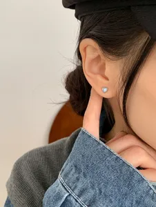 Detail shot of a delicate heart-shaped moonstone stud earring on an ear