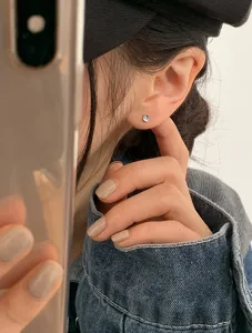 Detail view of a mini iridescent moonstone stud earring worn on the ear for daily style