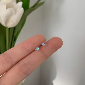 Detailed close-up view of mini iridescent moonstone stud earrings with a four-claw silver setting