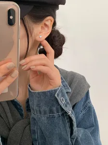 Close-up detail of a minimalist heart-shaped moonstone stud earring worn on the ear
