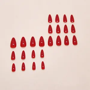 Detailed view of red almond-shaped press-on nails set on neutral background