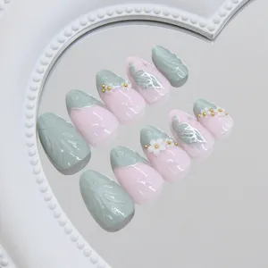 Vue détaillée de faux ongles vert et rose avec des motifs 3D de fleurs et d'ailes de papillon.