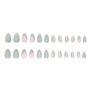 24 faux ongles vert et rose avec motifs d'ailes de papillon et fleurs décoratives.