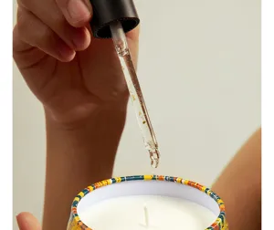 Detail shot of scented soy wax candle in decorative tin jar with essential oil dropper.