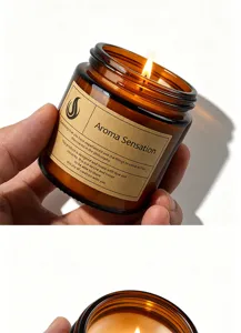 Amber glass scented soy candle jar with elegant kraft paper label and warm glow.