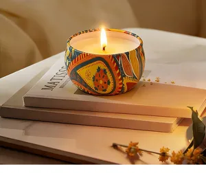 Detailed shot of soy wax scented candle in decorative metal tin jar with cozy warm glow.