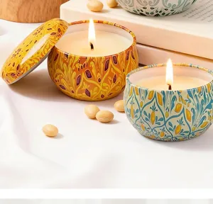 Macro shot of burning aromatherapy candles in ornate vintage metal tins on white cloth.