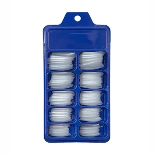 Vista macro de puntas de uñas transparentes en caja azul con 10 compartimentos