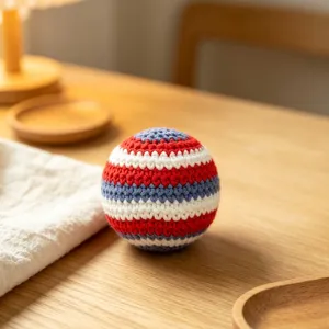 Detailed macro view of handmade red white and blue striped crochet stress ball on table
