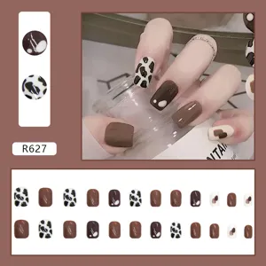 Close-up detail of brown and cow print short square press-on nails set with 24 pieces