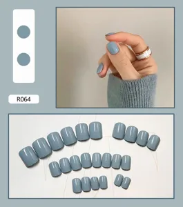 Dettaglio di 24 unghie finte blu polvere lucide e mano che indossa il set completo