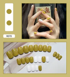 Dettaglio di un set da 24 pezzi di unghie finte lucide color giallo senape e bianco.