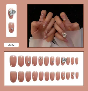 Vue détaillée de l'ensemble d'ongles rose nude avec breloque cœur et aperçu sur modèle