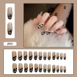 Vue macro détaillée de faux ongles tendance à motif léopard avec perles et décorations en strass.