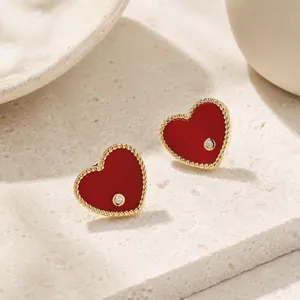 Detailed macro shot of 18K gold-plated red heart stud earrings with zircon