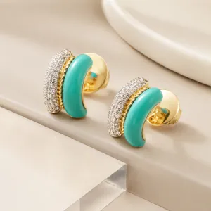 Detailed view of 18K gold C-hoop earrings featuring green enamel and sparkling pave zircons