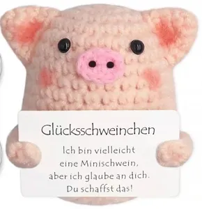 Detailed view of handmade crochet pink pig toy holding a cute positive message card.